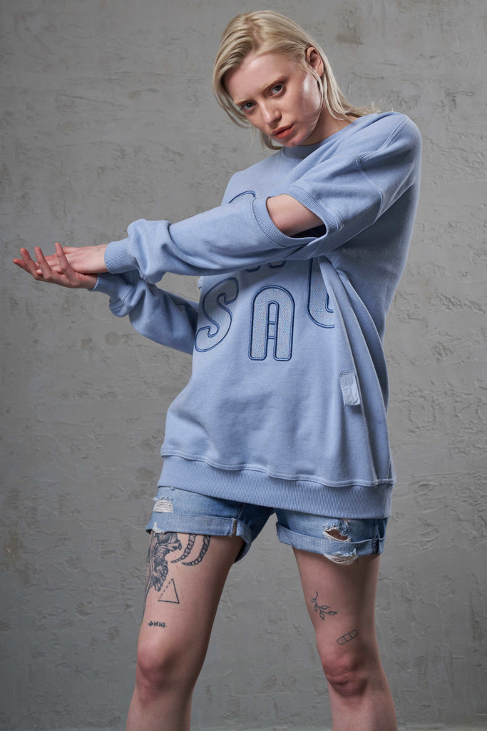 girl with tattoos showing her ice blue ethical summer crewneck sweats' split arms
