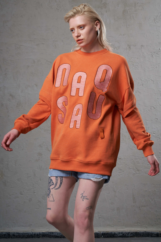 girl with tattoo in amazing orange cutout eco friendly sweatshirt and denim shorts