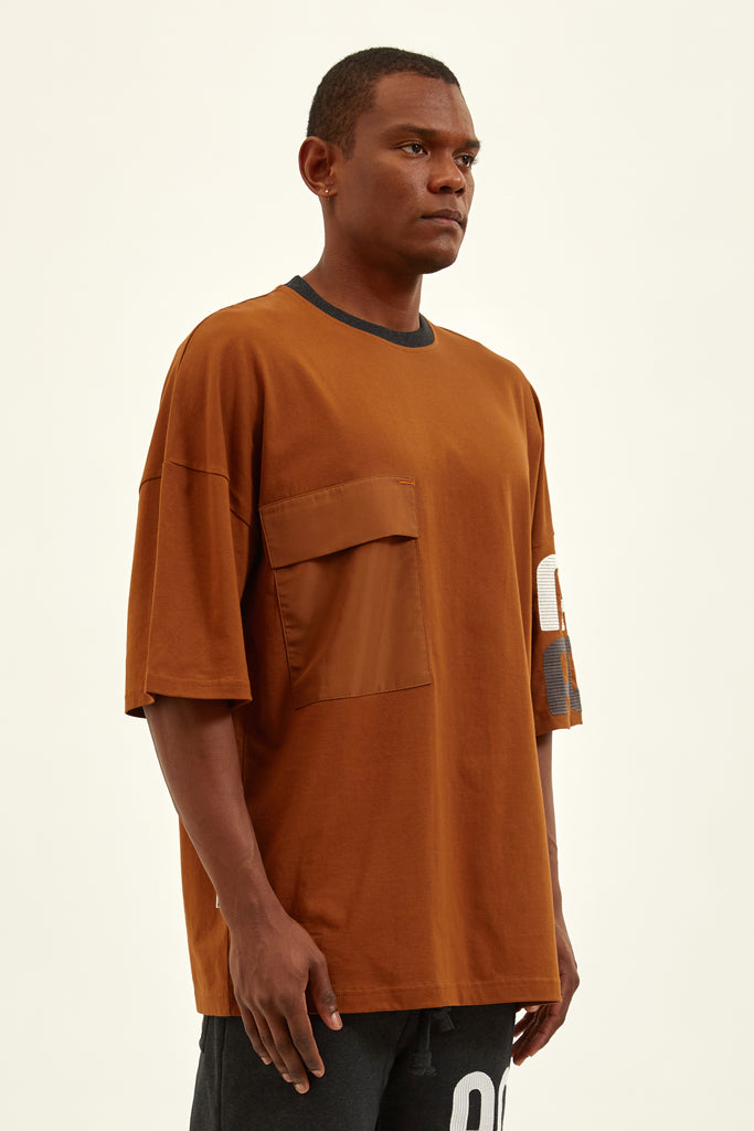 side of a kandy brown oversize loose fit t-shirt with a flap pocket